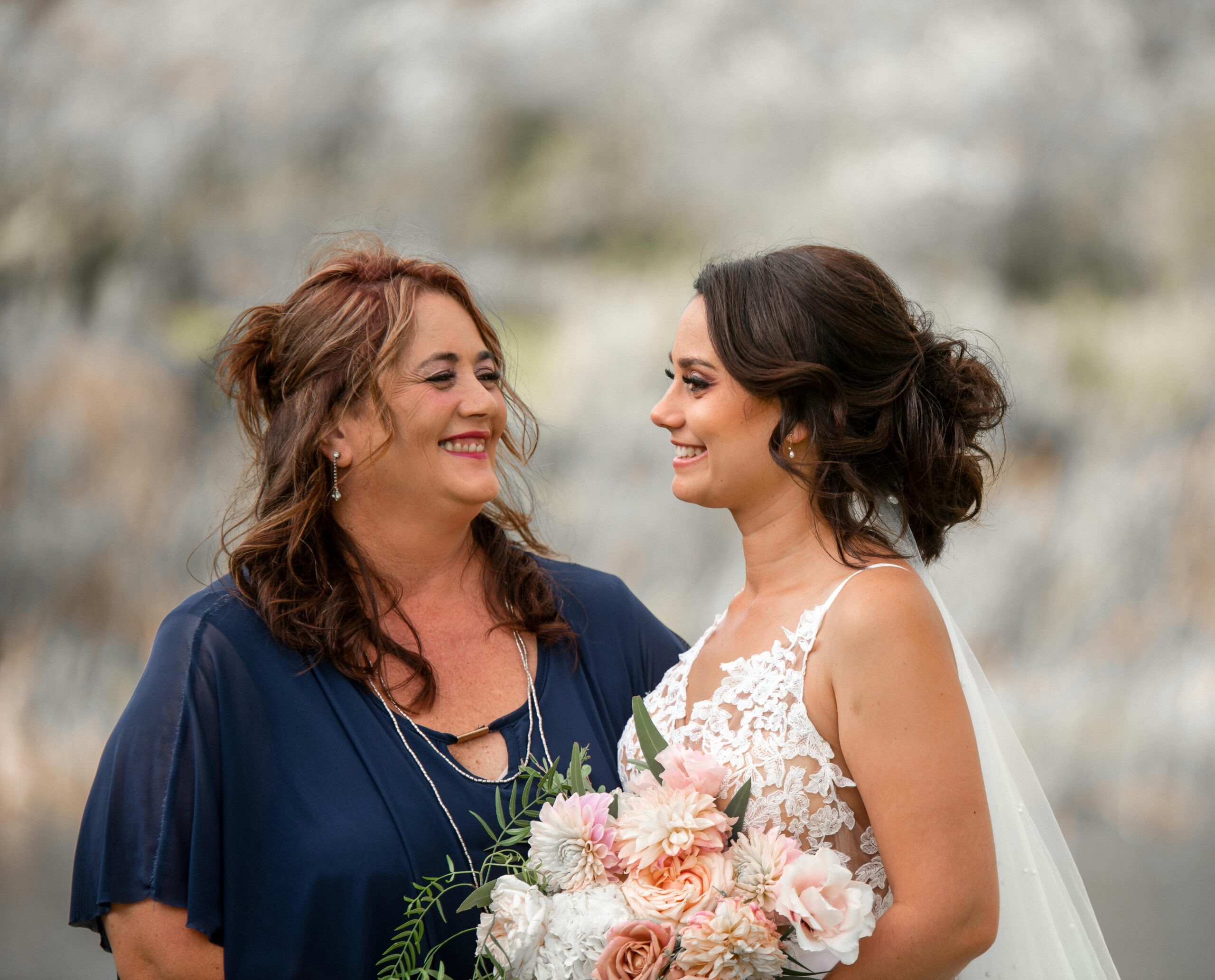 Bride and bridesmaid sharing a happy moment outdoors. Beautiful wedding day scene.